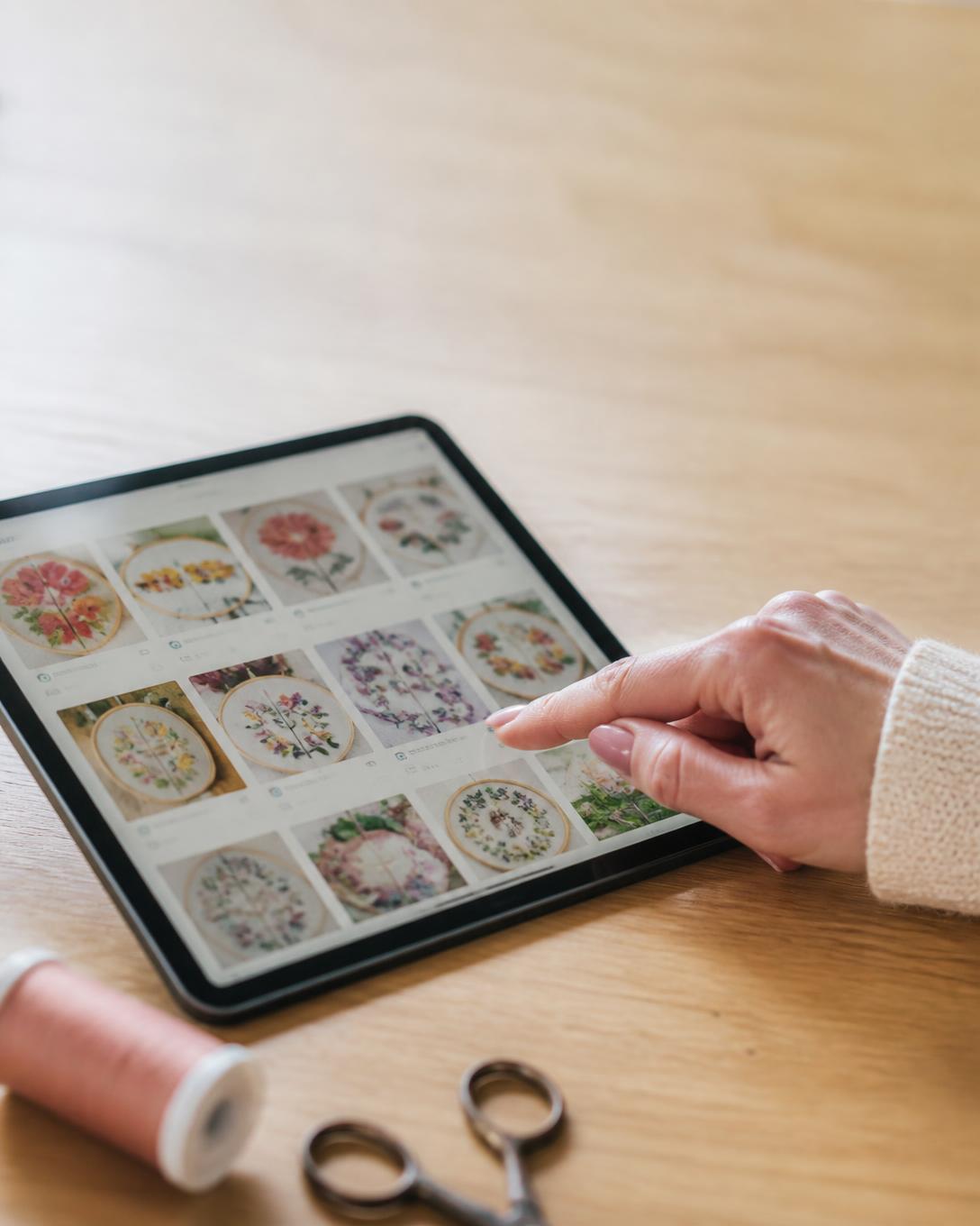 Mão a escolher um risco de bordado numa biblioteca digital num tablet